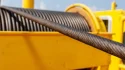Close-up of heavy-duty industrial crane wire rope wound onto a bright yellow winch drum spool, demonstrating premium multi-strand IWRC construction for lifting applications.