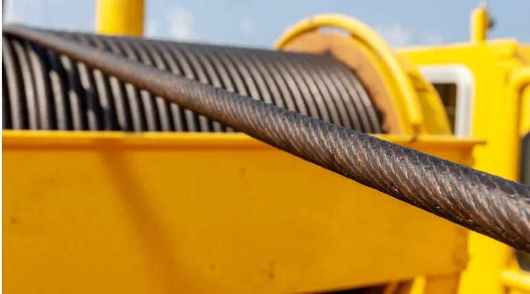 Close-up of heavy-duty industrial crane wire rope wound onto a bright yellow winch drum spool, demonstrating premium multi-strand IWRC construction for lifting applications.