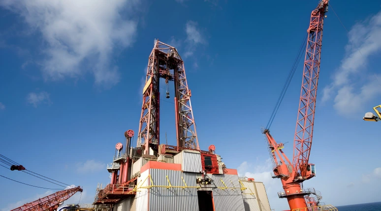 Offshore drilling rig platform with heavy-duty lattice boom crane under clear sky