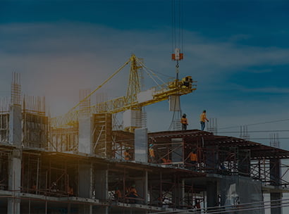 Construction site with yellow tower crane and workers on structural steel reinforced concrete building frame.